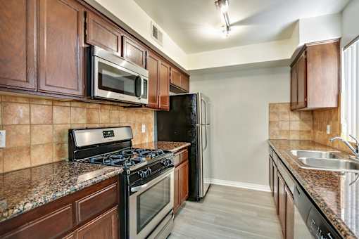 A kitchen with brown cabinets and black appliances.