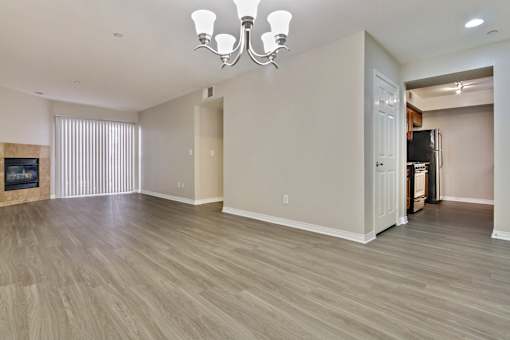 A spacious living room with a chandelier and hardwood flooring.