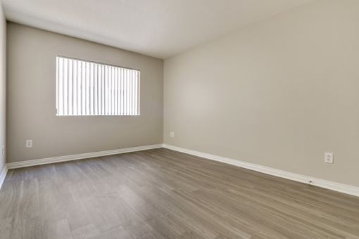 A room with a window and wooden flooring.