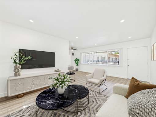 A living room with a black marble coffee table and a flat screen TV mounted on the wall.
