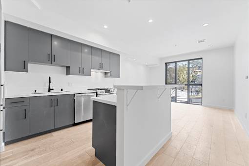 A modern kitchen with wooden floors and grey cabinets.