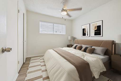 A bedroom with a bed, pillows, and a ceiling fan.