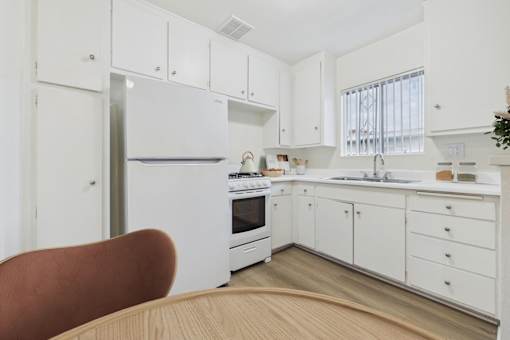 A kitchen with white cabinets and a refrigerator.