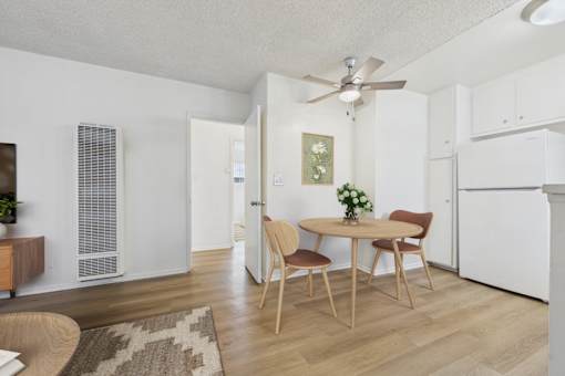 A dining room with a table set for two and a ceiling fan.