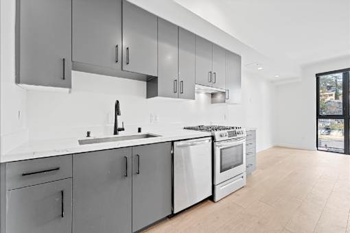 A modern kitchen with a white countertop and stainless steel appliances.