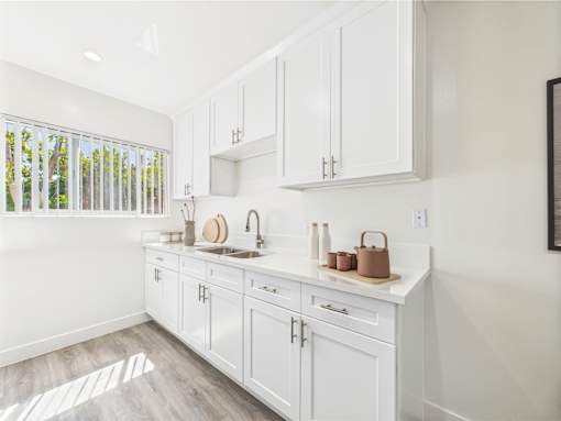A kitchen with white cabinets and a window.