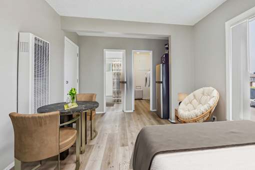 A bedroom with a bed, chair, and dining table.