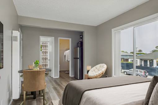 A bedroom with a bed, chair, and a dining table.