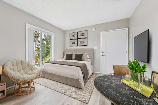 A bedroom with a bed, chair, and a television.