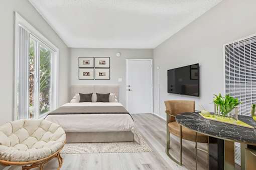 A bedroom with a bed, chair, and television.