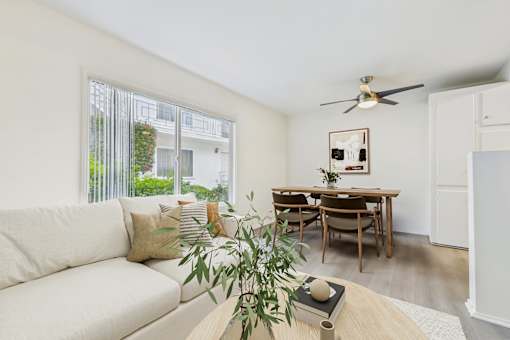 A living room with a white couch, a wooden table, and a ceiling fan.