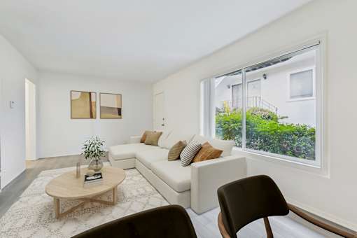 A living room with a white couch, a coffee table, and a chair.