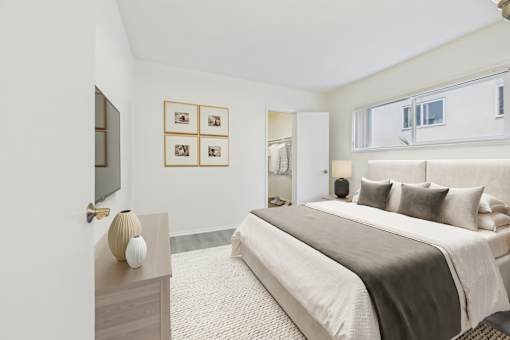 A bedroom with a large bed and a nightstand with a lamp on it.
