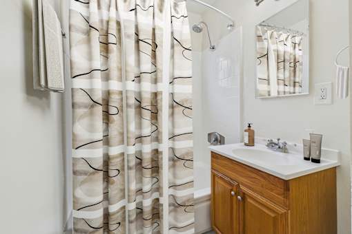 A bathroom with a white sink and a shower curtain with black lines.