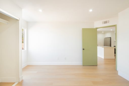 a living room with white walls and a green door