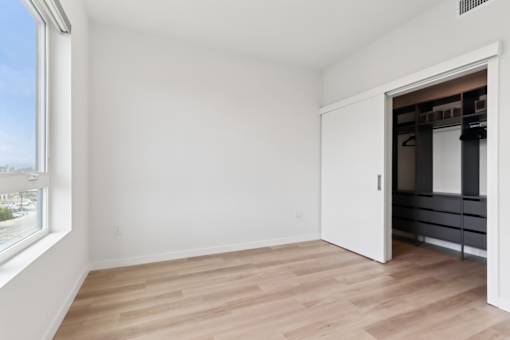 A room with a white door and a window with a view of the city.