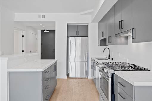 A modern kitchen with a refrigerator, stove, and cabinets.