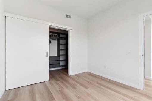 A white door opens to a kitchen with white walls and wood flooring.