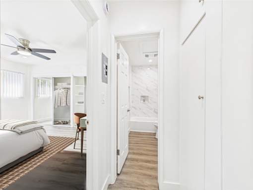 A bedroom with a bed, chair, and a fan.