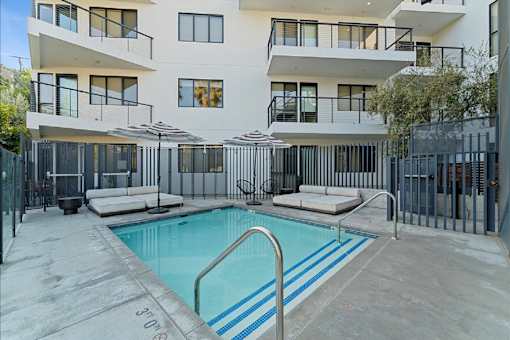 A swimming pool in front of a white building with black railings.