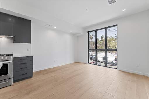 A spacious kitchen with a stove top oven and a sliding glass door leading to a balcony.
