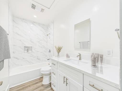 A white bathroom with a marble wall and a toilet.