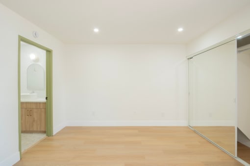 a living room with white walls and a sliding glass door to a bathroom