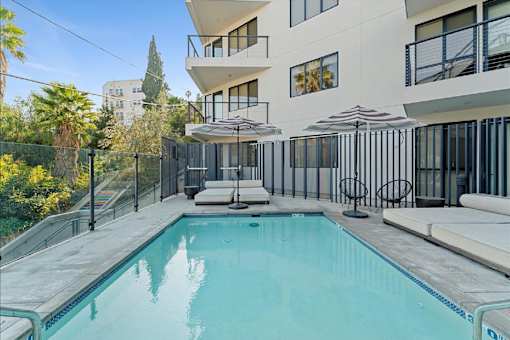 A swimming pool in a residential area with a white building in the background.