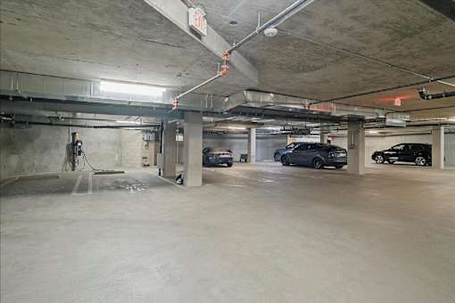 A parking garage with a few cars and a hose.