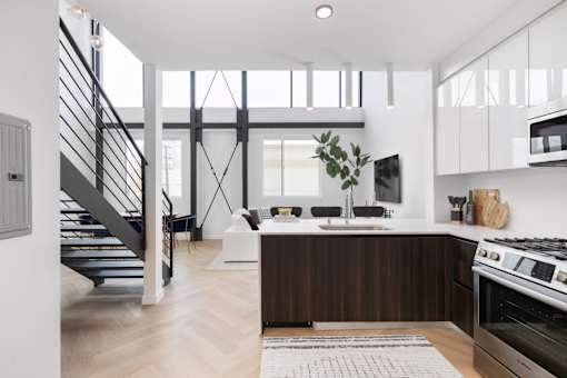 a kitchen and living room with a staircase in a house