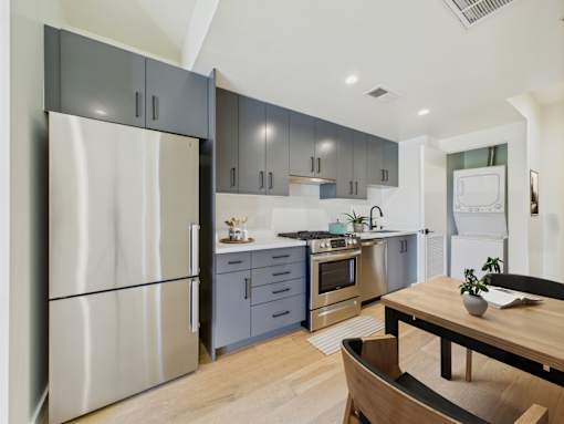 A modern kitchen with a wooden table and stainless steel appliances.