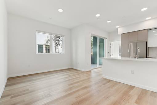 A spacious room with wooden flooring and a large window.