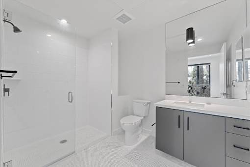 A white bathroom with a toilet, sink, and shower.