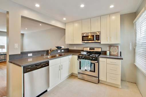 the kitchen has stainless steel appliances and white cabinets