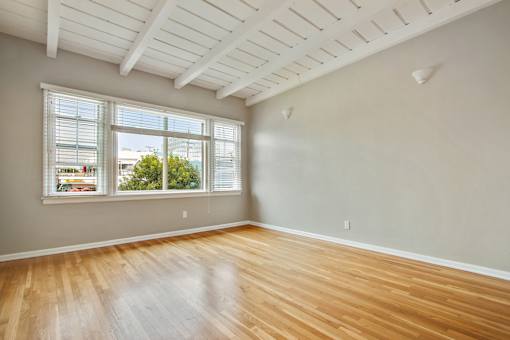 an empty living room with wood floors and a window