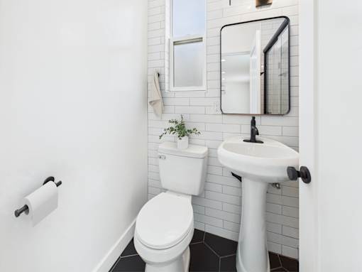 A white toilet sits next to a white pedestal sink in a small bathroom.