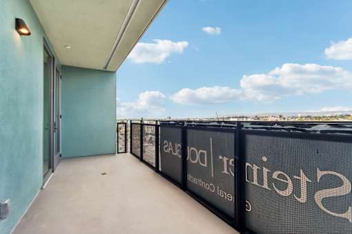 A balcony with a black fence and a blue wall.