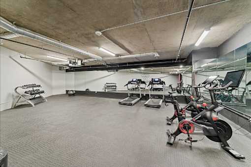 A gym with a grey carpet and a concrete ceiling.