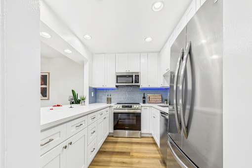A modern kitchen with white cabinets and stainless steel appliances.