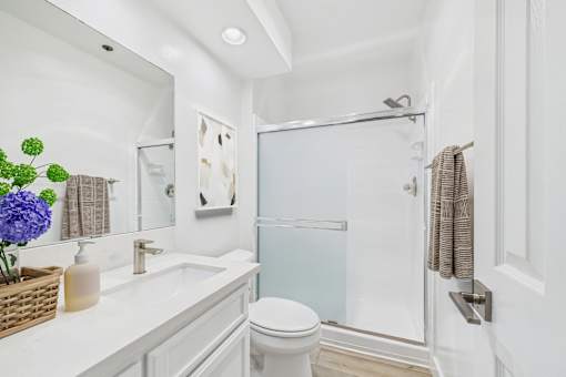 A white bathroom with a toilet, sink, and shower.