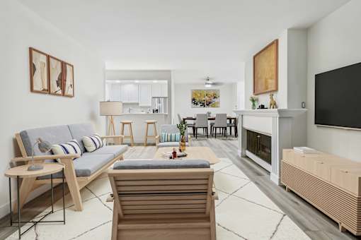 A modern living room with a grey sofa, wooden chairs, and a fireplace.