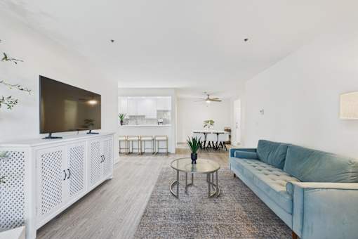 A living room with a white cabinet, a blue couch, and a glass table.