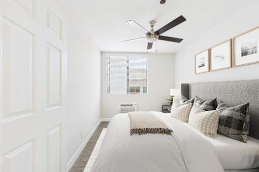 A bedroom with a bed, pillows, and pictures on the wall.