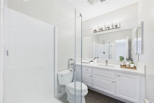 A white bathroom with a toilet, sink, and mirror.