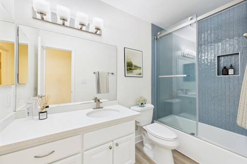 A bathroom with a white toilet, sink, and mirror.