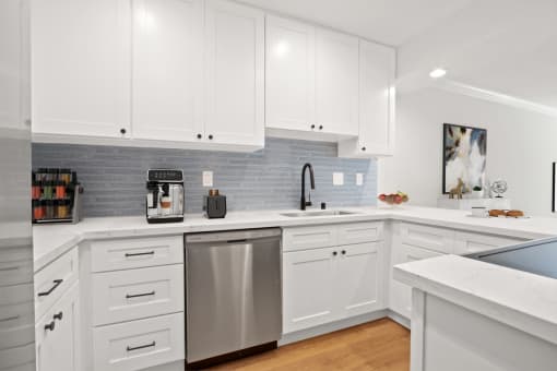 a white kitchen with stainless steel appliances and white cabinets