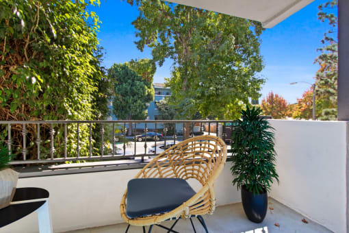 a balcony with a rattan chair and a plant on it