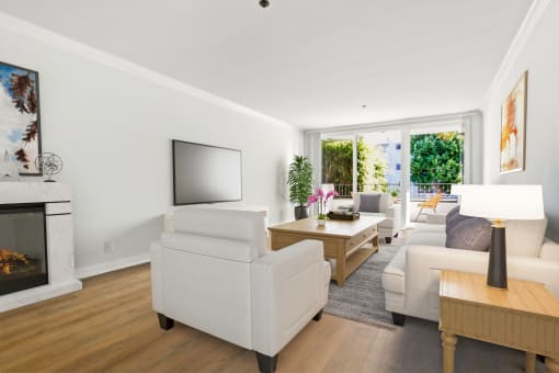 a living room with white furniture and a tv on the wall