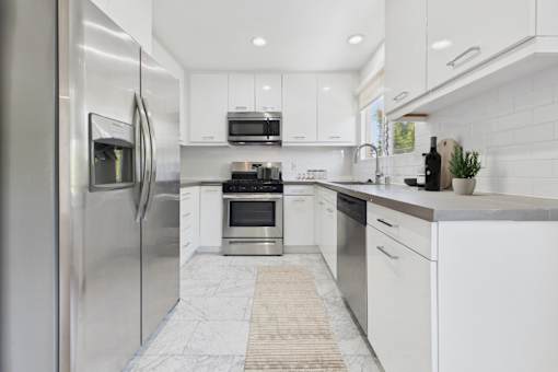 A modern kitchen with white cabinets and stainless steel appliances.