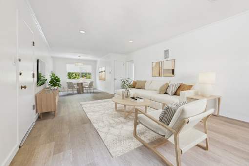 A living room with a white couch and a wooden floor.